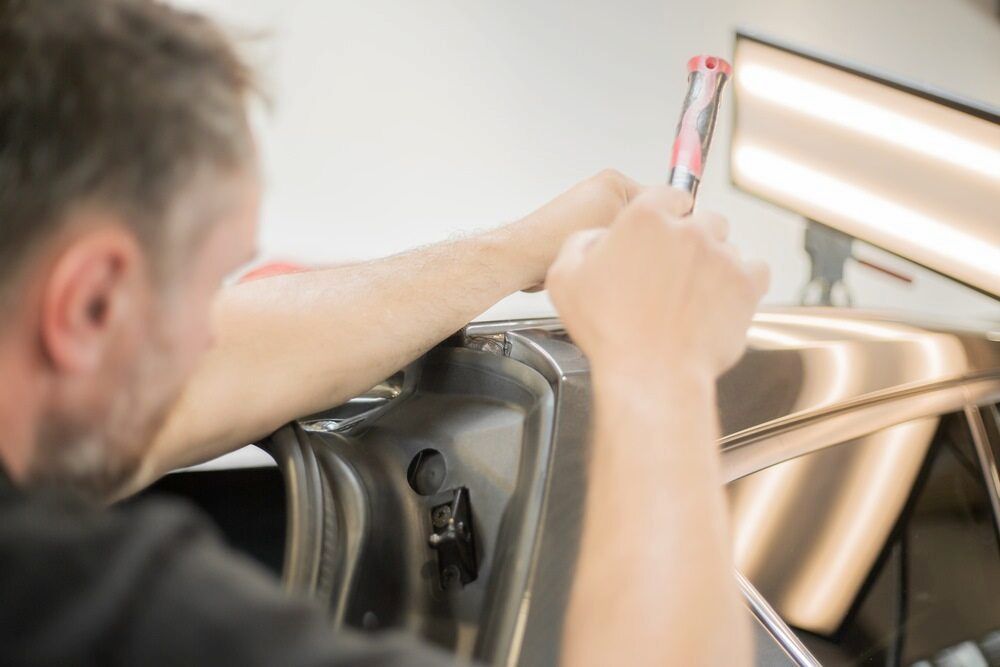A Man is Working on a Car Door With a Wrench — Seabreeze Auto Body in Coffs Harbour, NSW