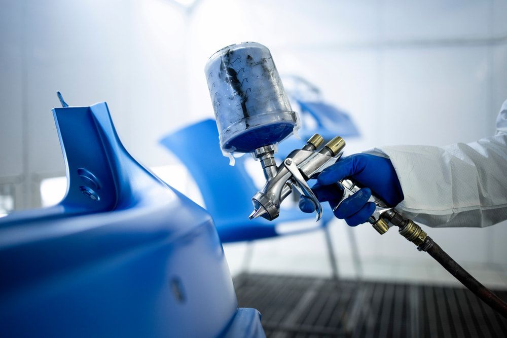 A Person is Spray Painting a Blue Chair in a Paint Booth — Seabreeze Auto Body in Coffs Harbour, NSW