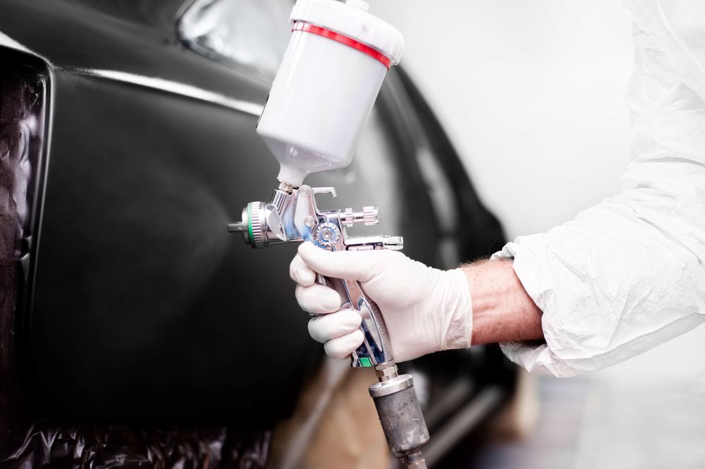 A Man Spray Painting a Car While Working — Seabreeze Auto Body in Coffs Harbour, NSW