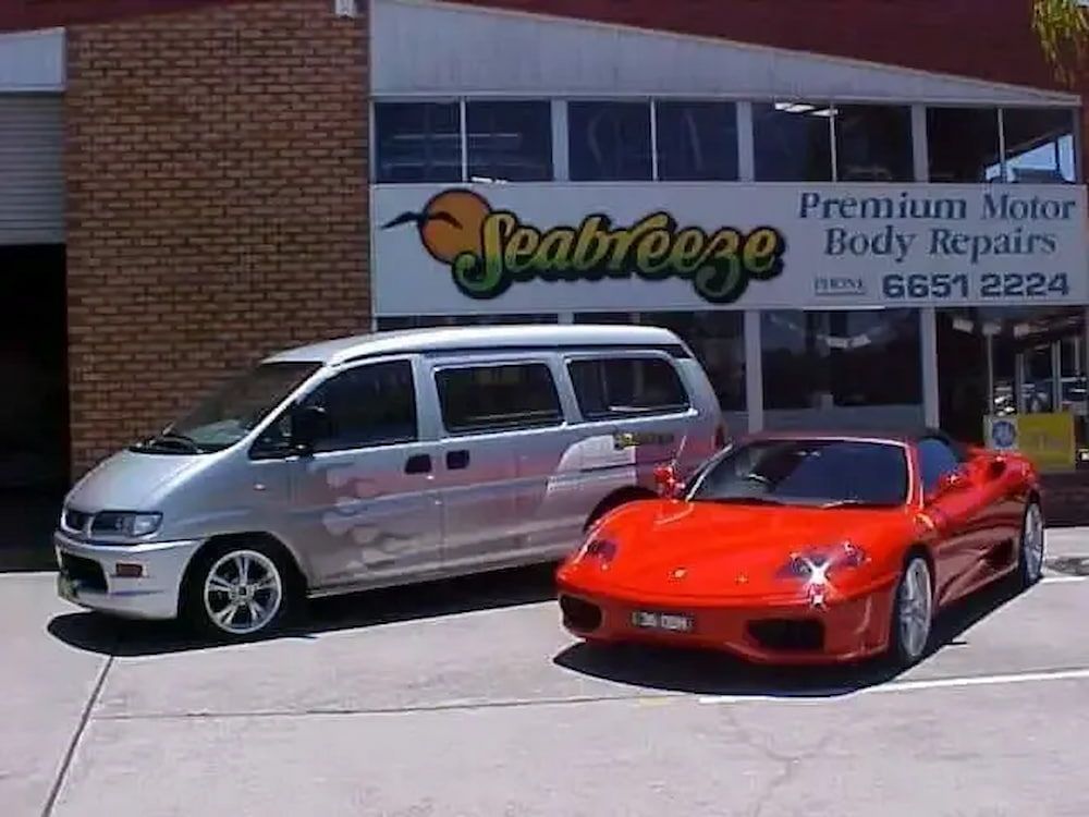 A Silver Van and a Red Sports Car Are Parked in Front of a Building That Says Seabreeze — Seabreeze Auto Body in Coffs Harbour, NSW