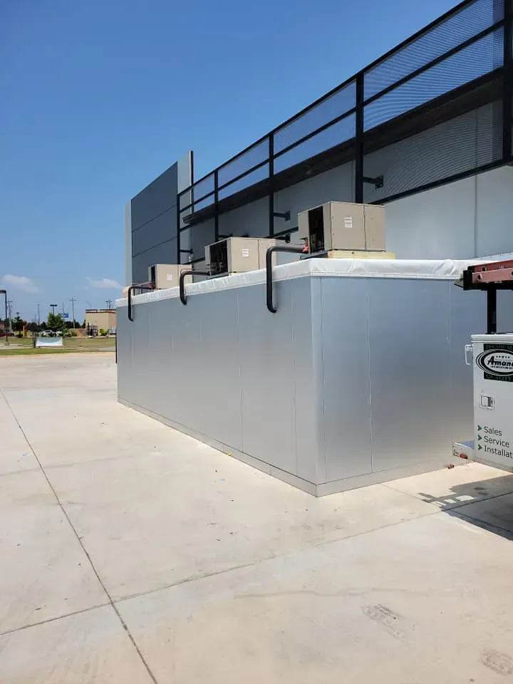 A large metal container is sitting in front of a building.