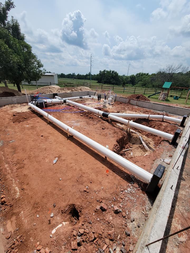 A bunch of pipes are laying in the dirt on a construction site.