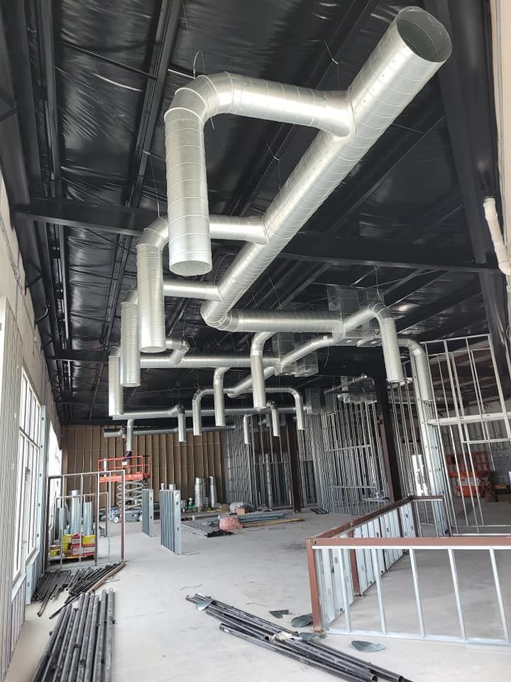 A building under construction with a lot of pipes hanging from the ceiling.