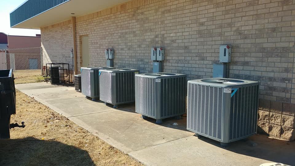 A row of air conditioners are sitting on the side of a brick building.