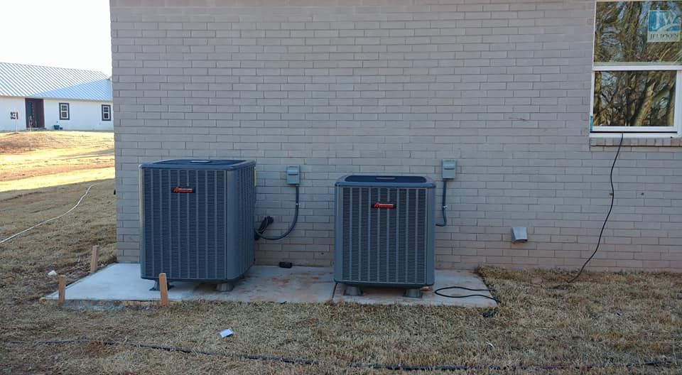 Two air conditioners are sitting on the side of a brick building.