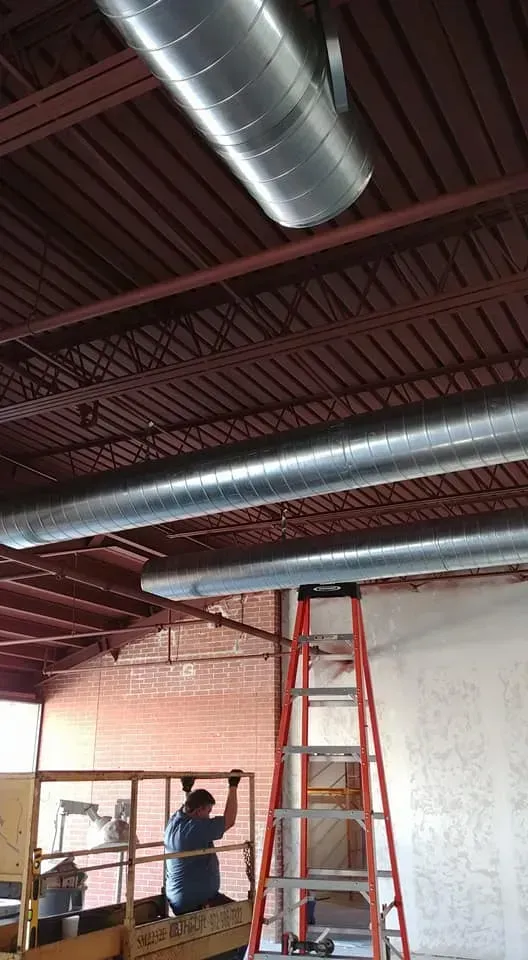 A man is standing on a lift working on a ceiling.