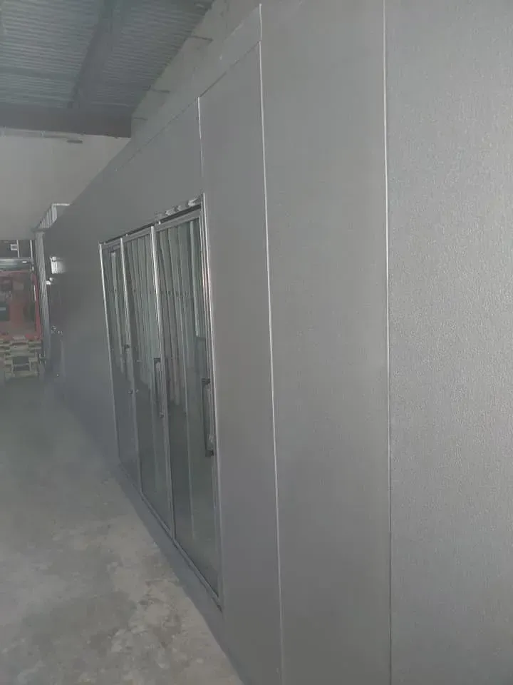 A row of stainless steel refrigerators are lined up in a room.