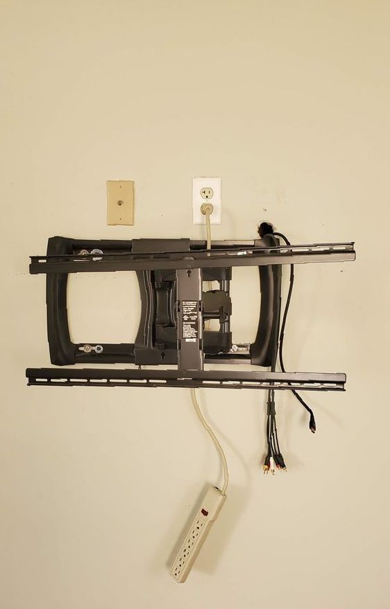 A tv mount with a power strip attached to it
