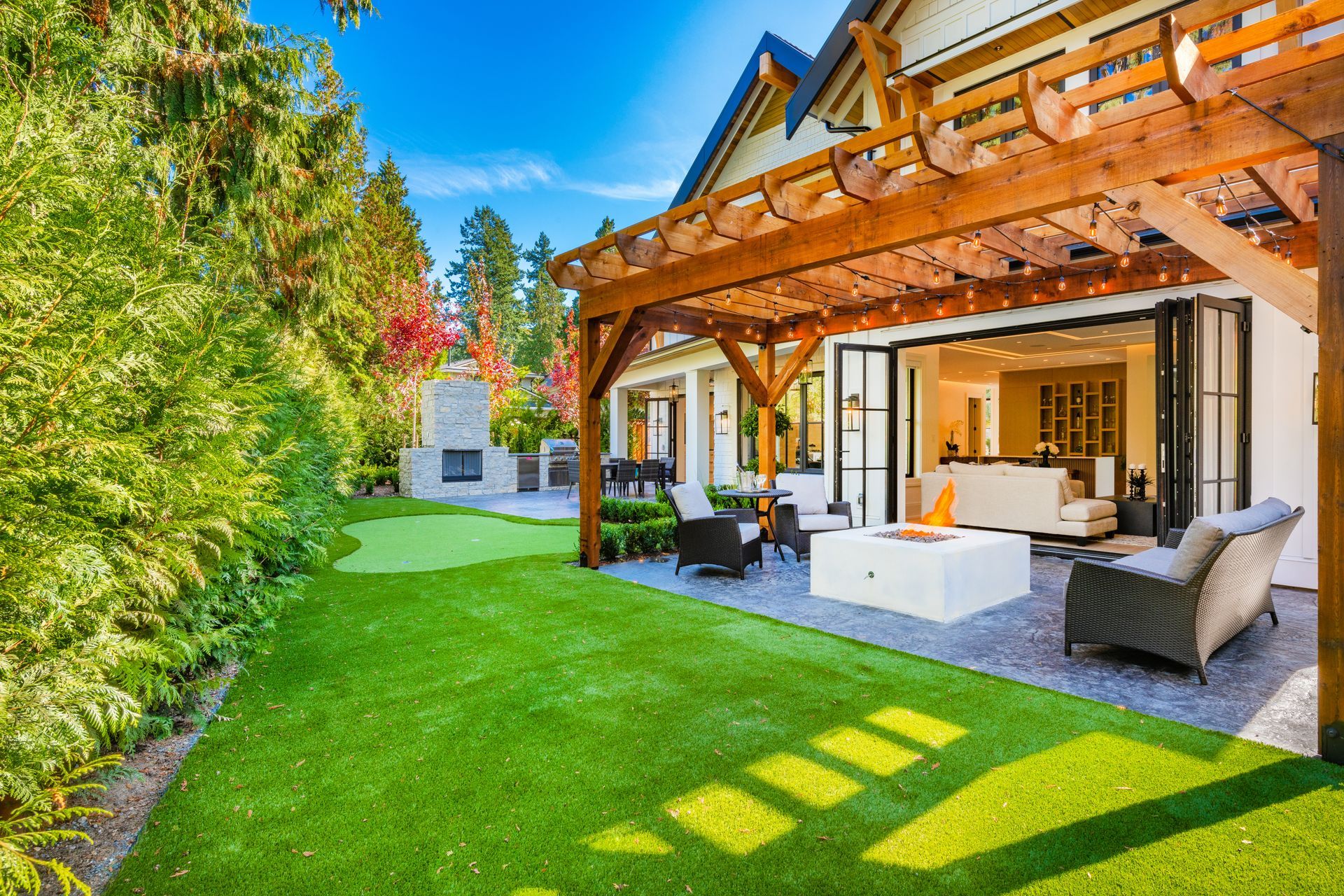 Backyard patio with a pergola, fire pit, and synthetic grass lawn.
