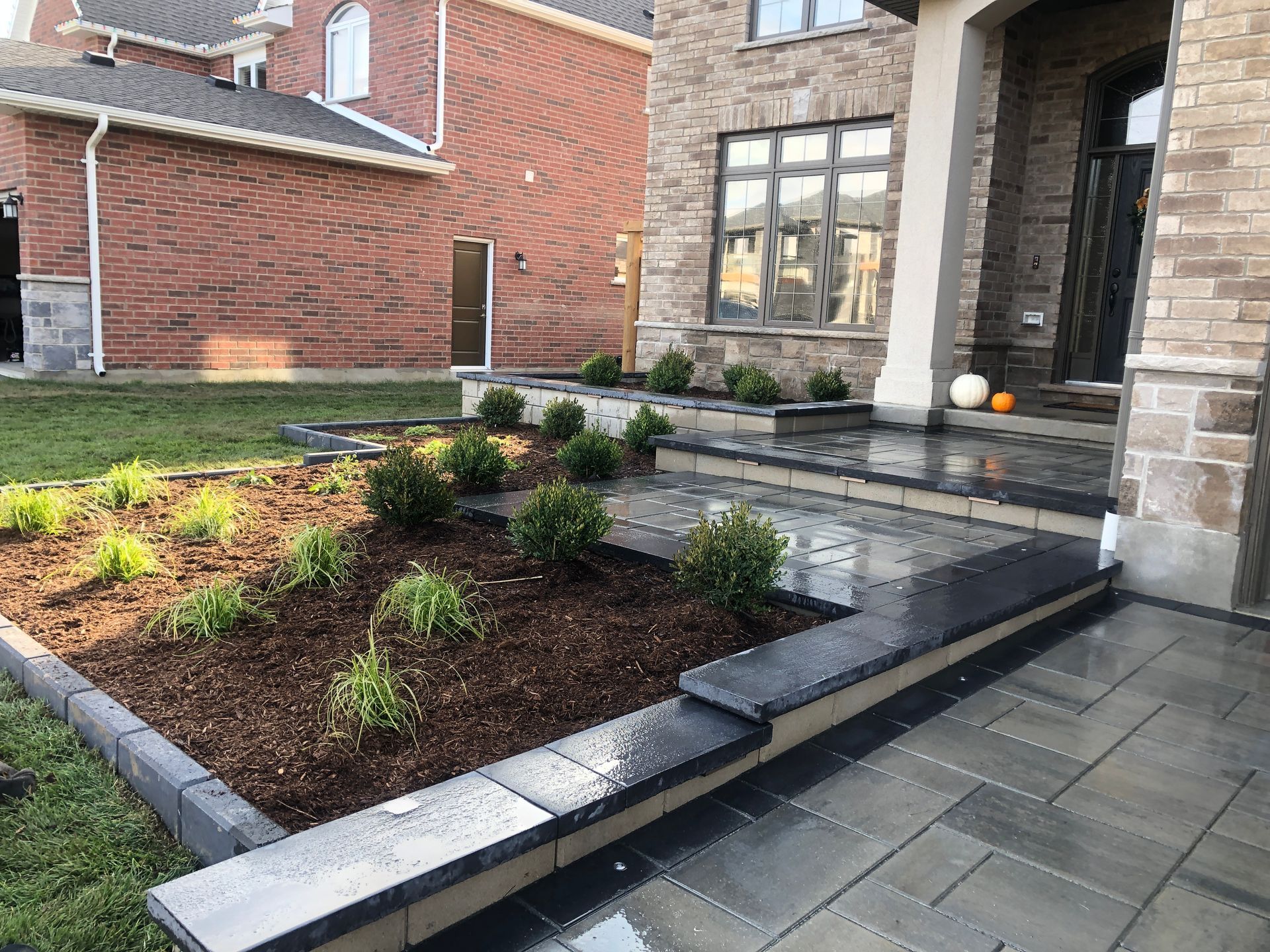 Brick home exterior with stone steps and landscaping featuring mulch and plants.