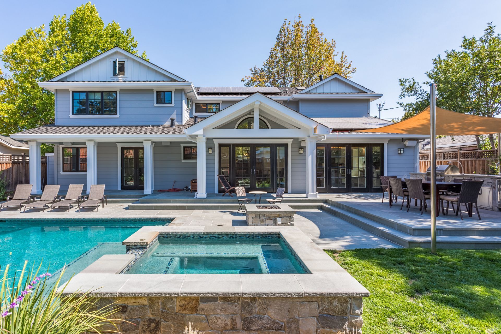 Backyard with a pool, spa, outdoor dining, and a blue house.