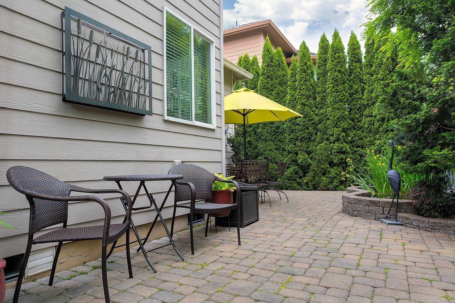 Patio with a table and chairs, a yellow umbrella, and a brick pathway.