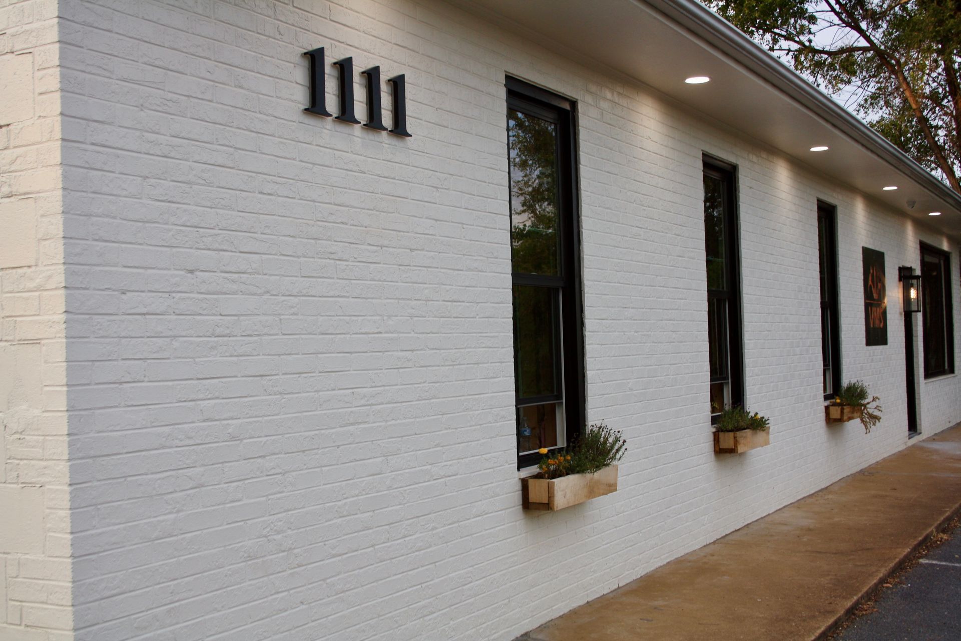White brick building exterior with narrow windows and flower boxes along a covered walkway
