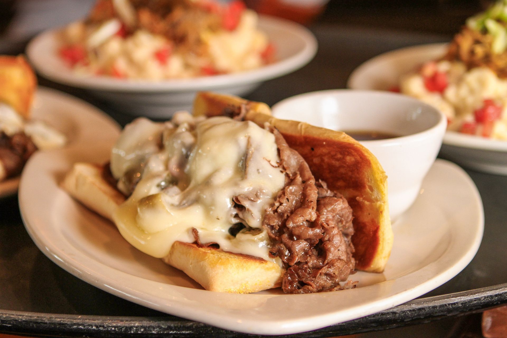A steak sandwich with cheese and gravy on a white plate