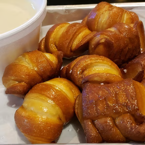 A tray of pretzels next to a bowl of dipping sauce