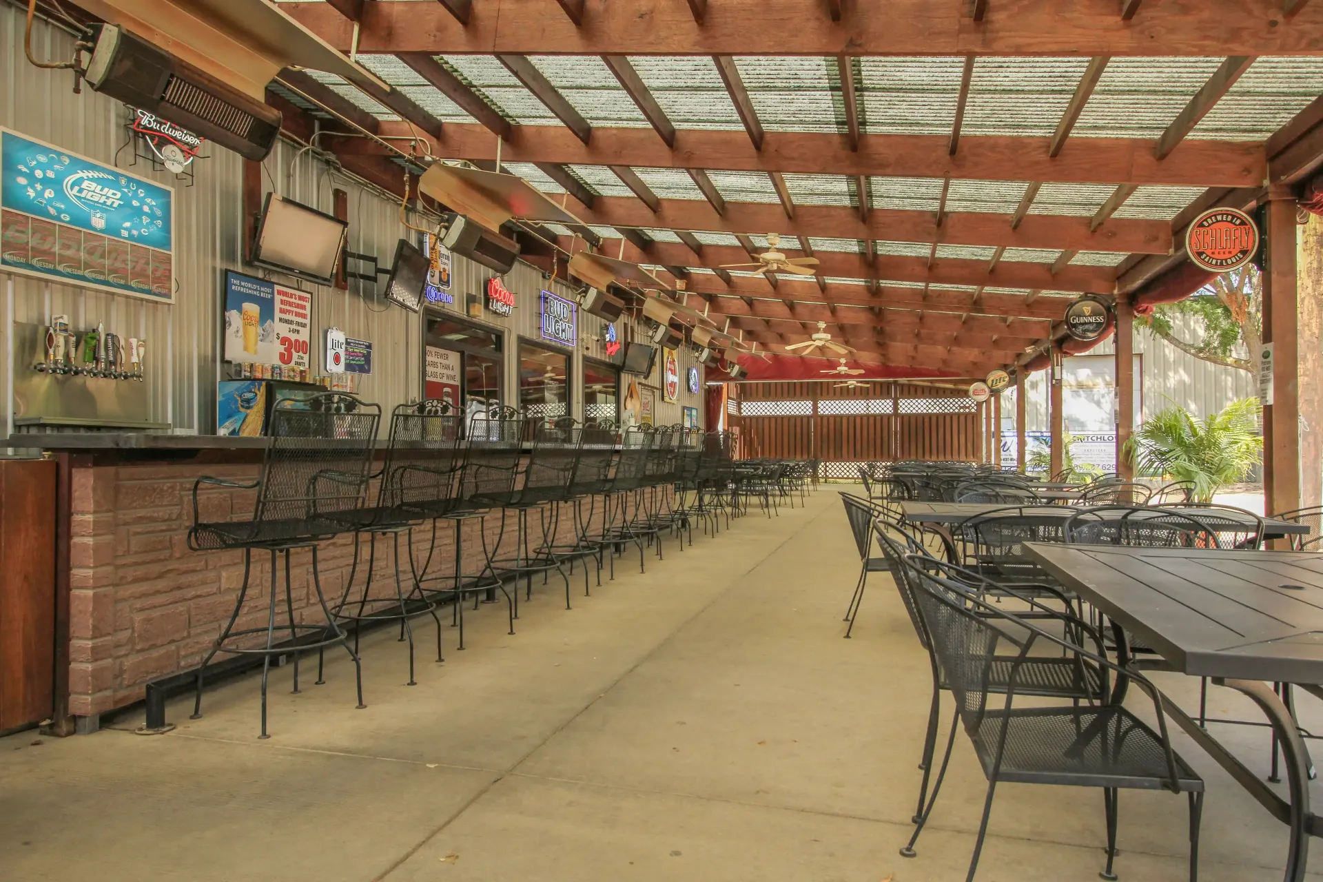 A restaurant with tables and chairs and a bar under a pergola.