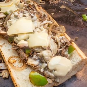 A sub sandwich with beef, cheese, onions and peppers on a bun.