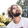 Man with curly hair and beard looking up outdoors in bright sunlight