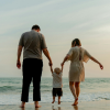 Family holding hands while walking on a beach at sunset