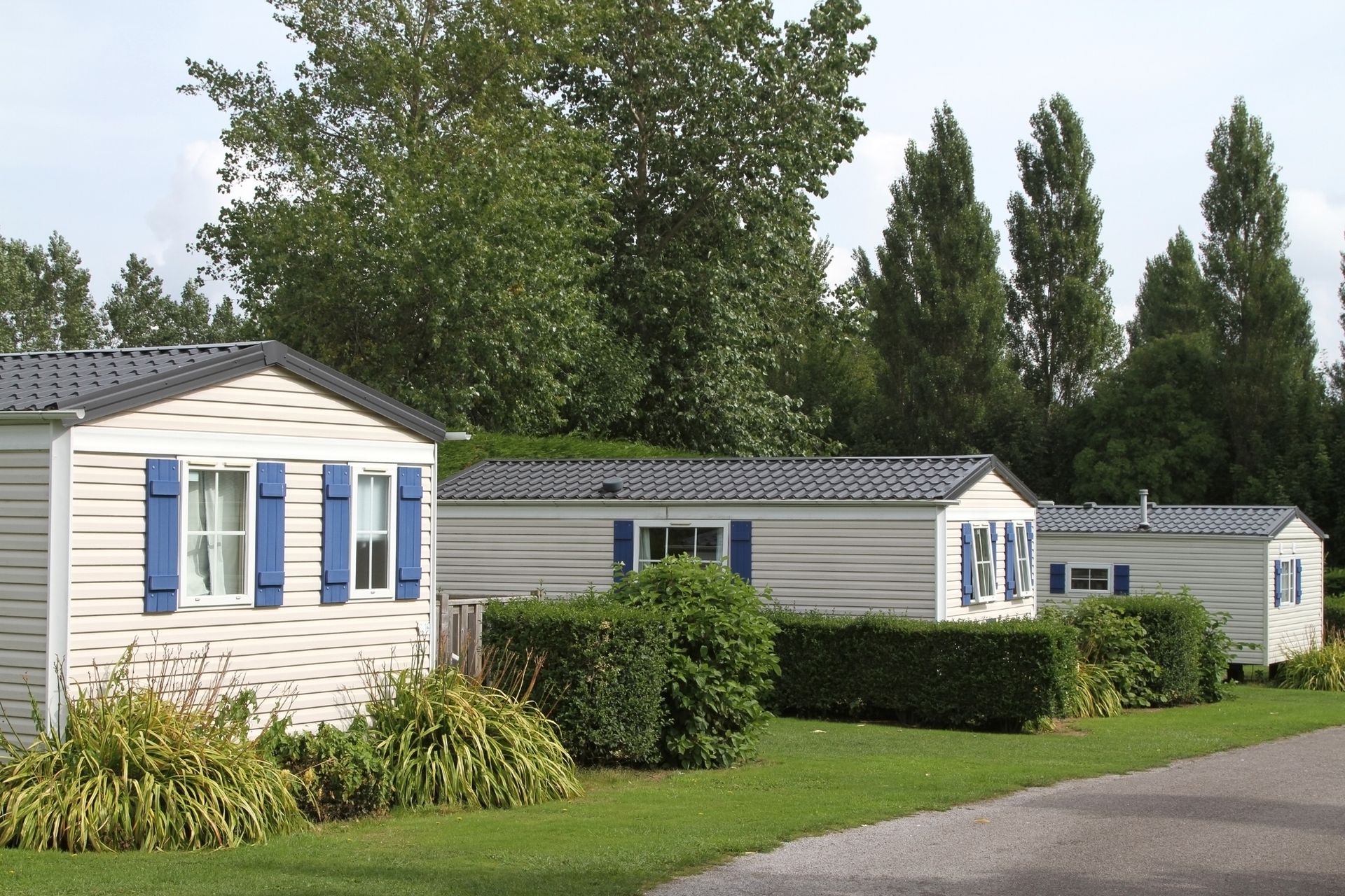 a row of mobile homes with blue shutters on the windows