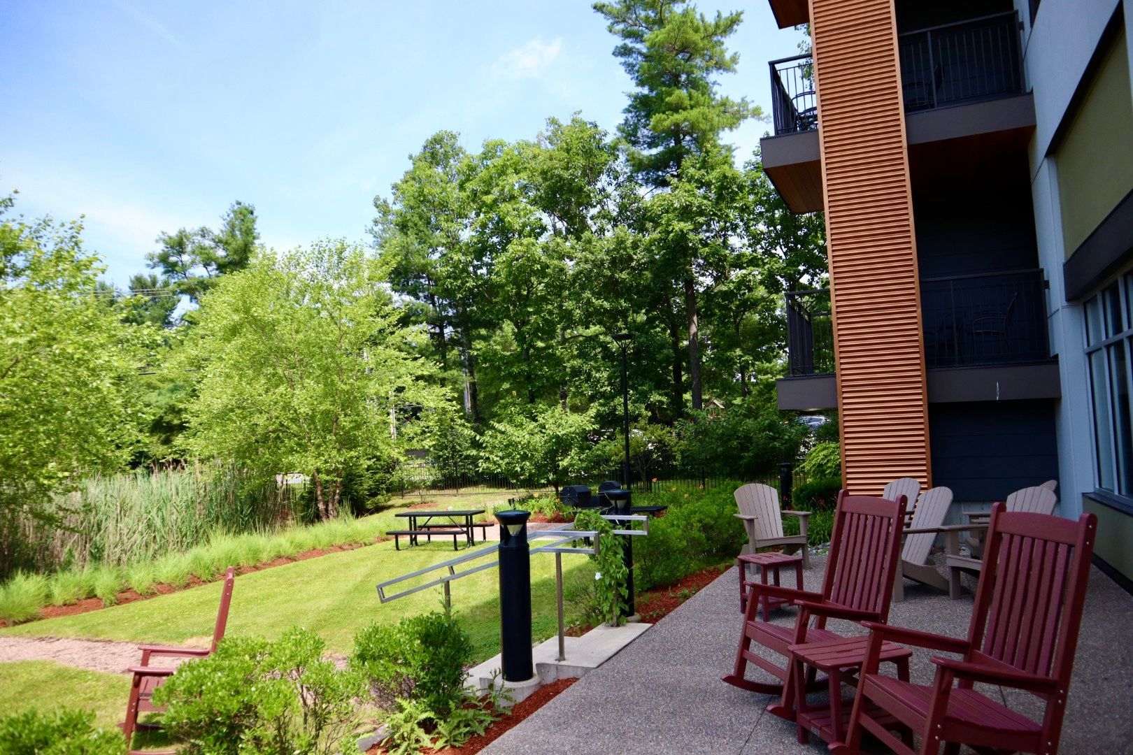 A patio with rocking chairs and a picnic table in front of a building.