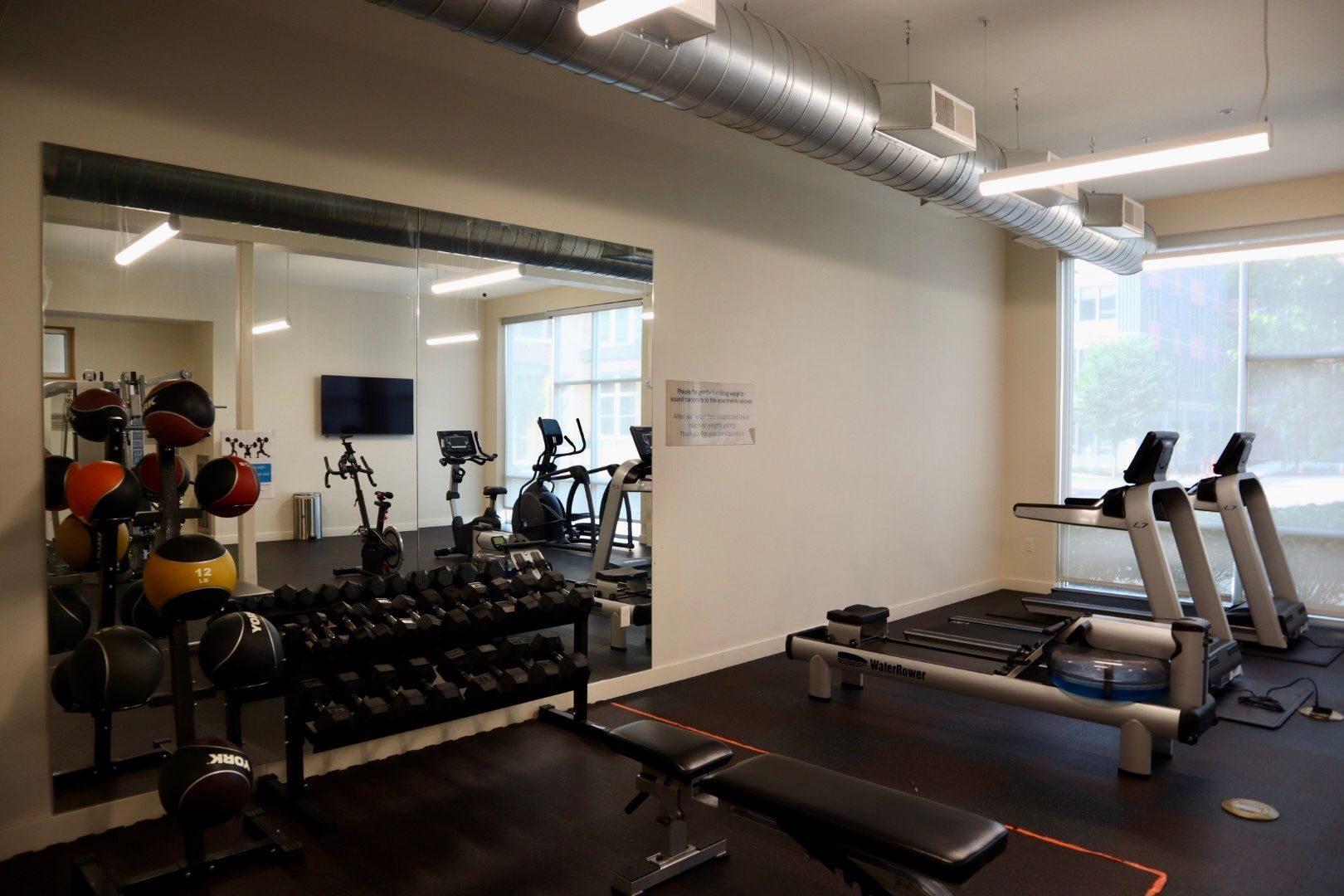 A gym with a lot of exercise equipment and a large mirror.