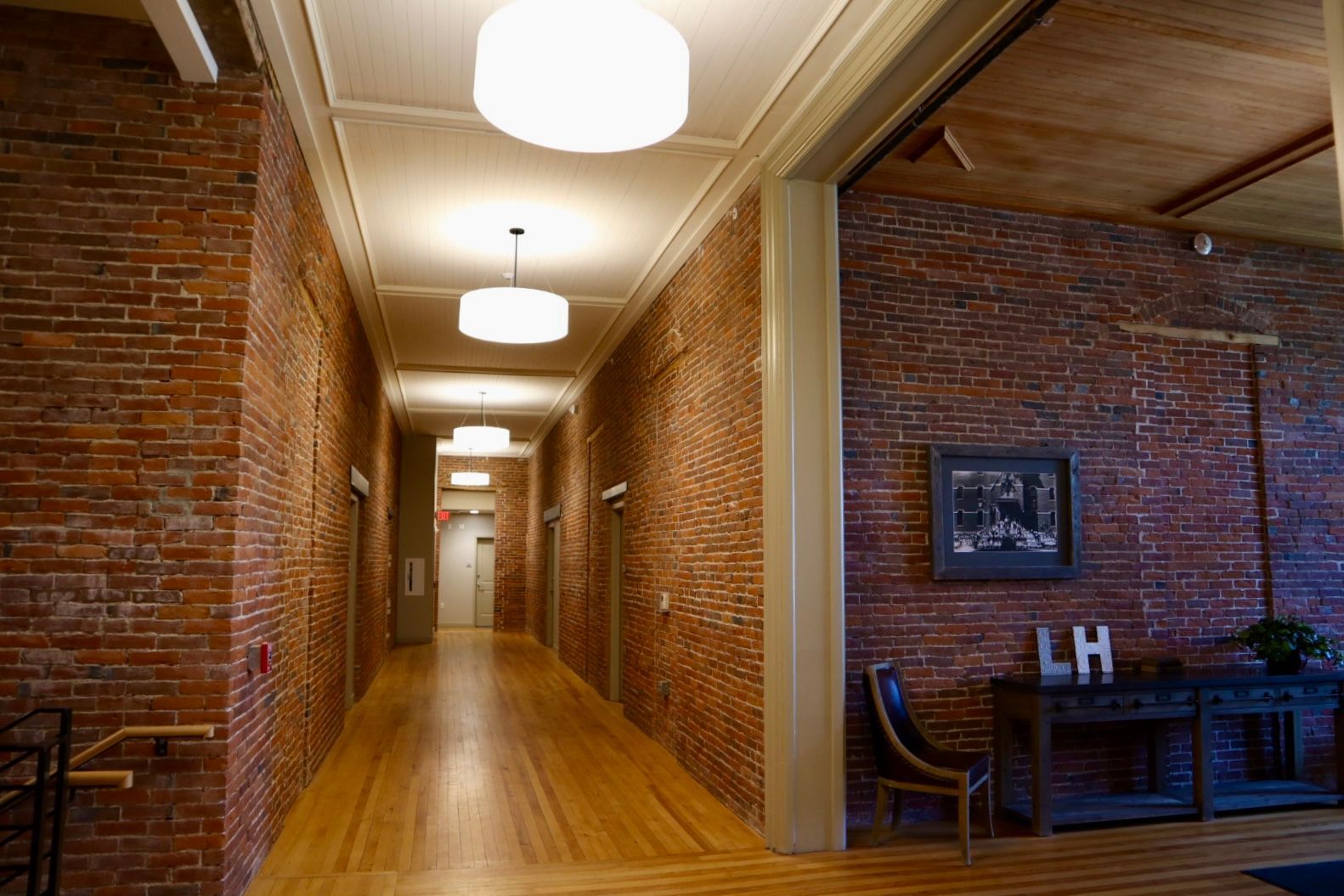 A long hallway with brick walls and wooden floors in a building.