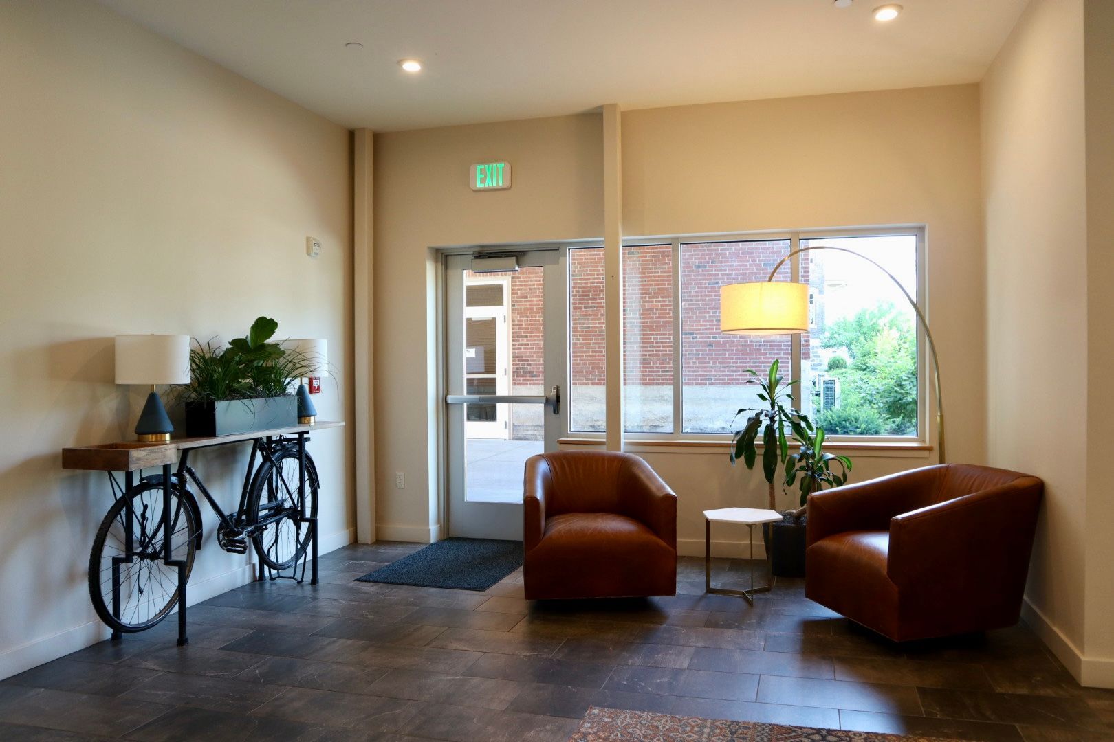 A living room with two chairs and a bicycle on the wall.
