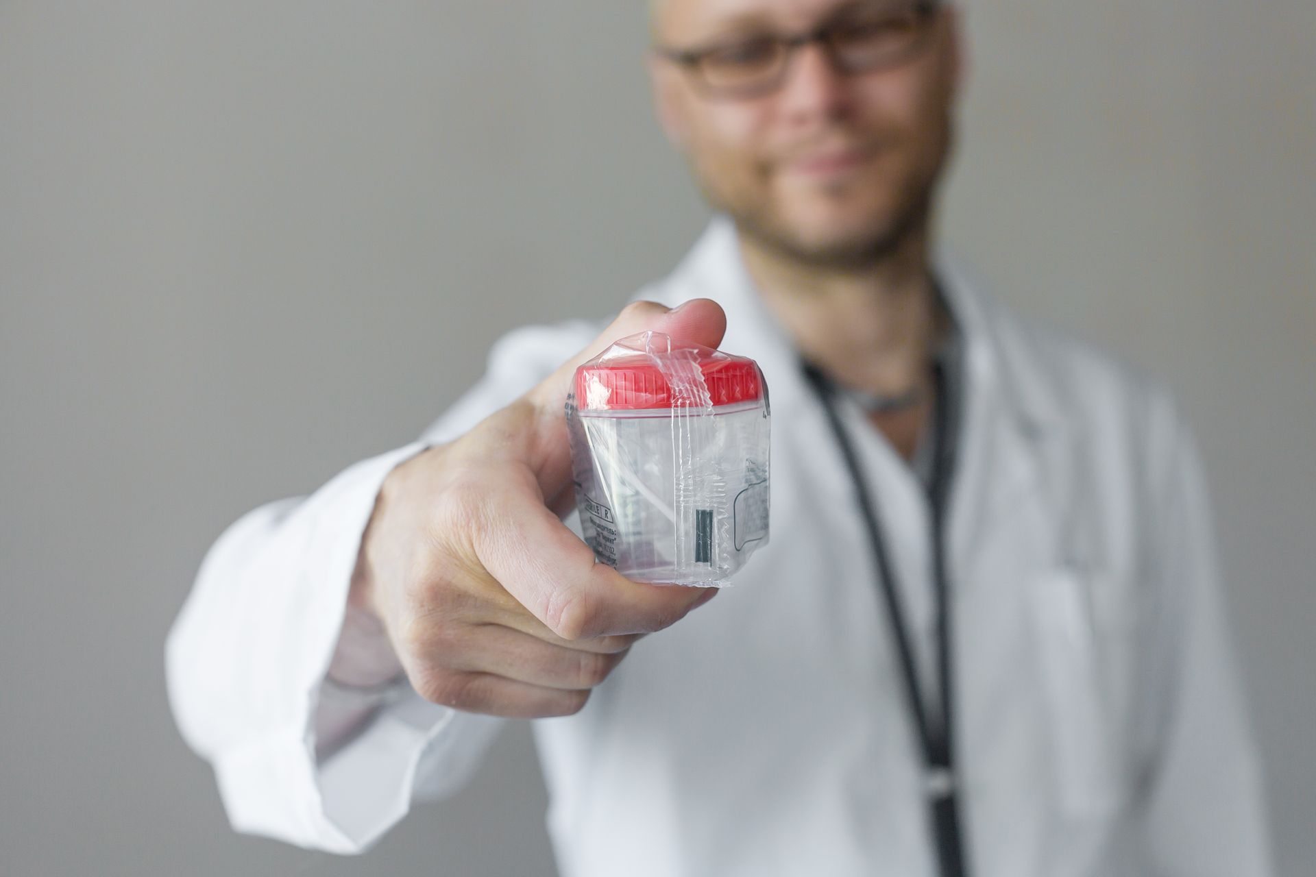 Person in blue gloves holding a urine sample labeled 