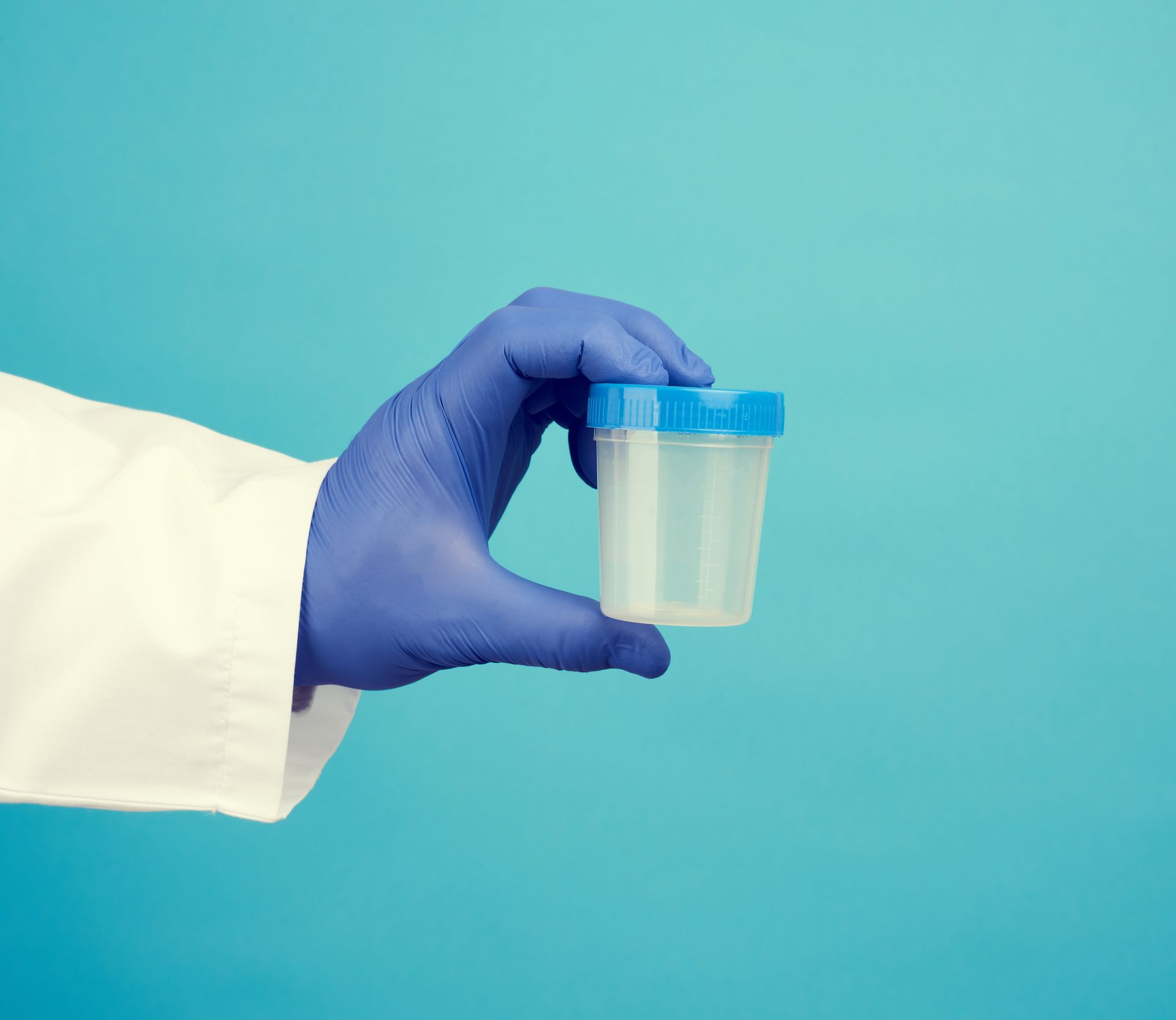 Person in lab coat and gloves handling petri dishes in a lab setting.