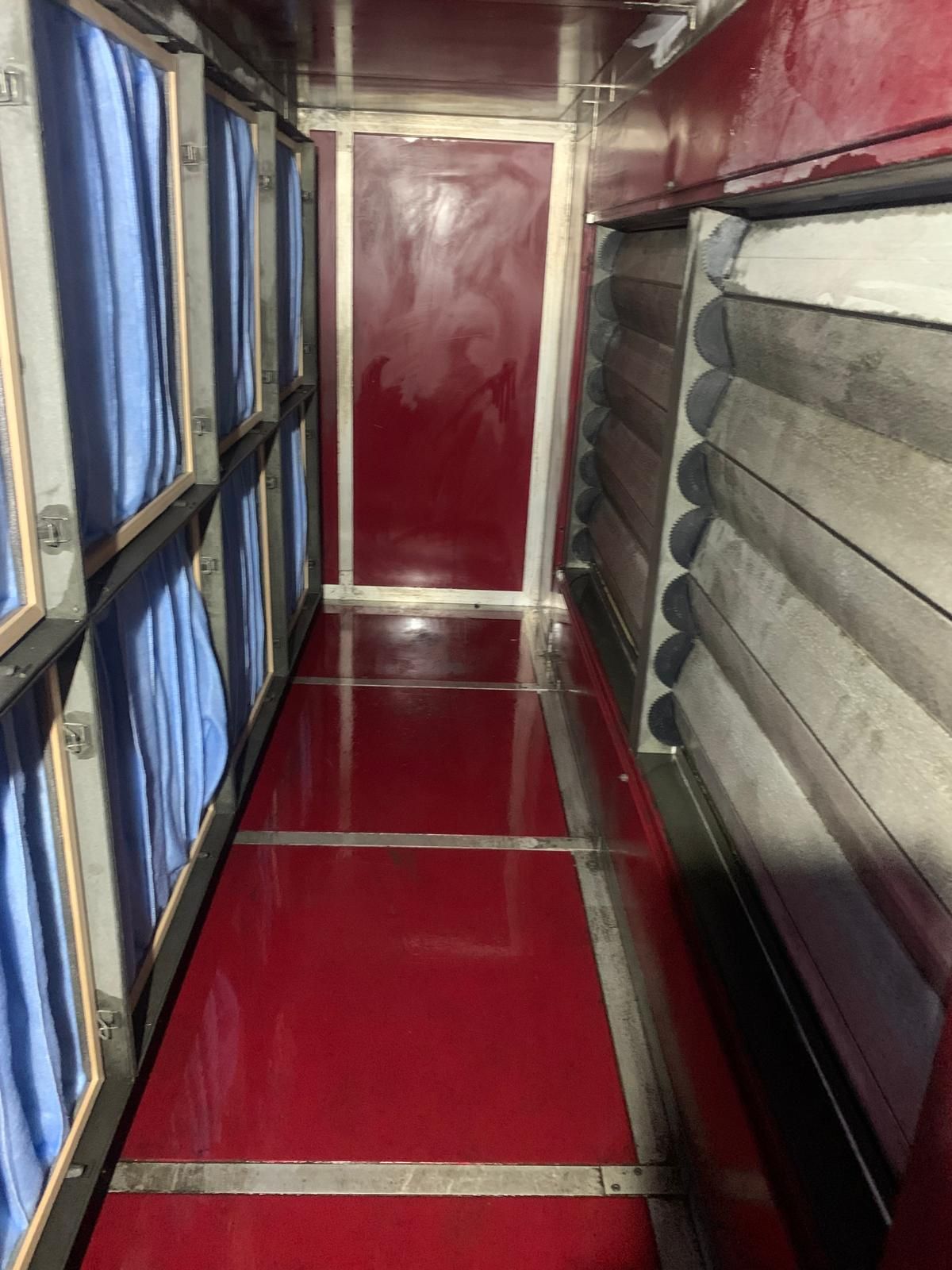 Un long couloir avec un sol rouge et des rideaux bleus.