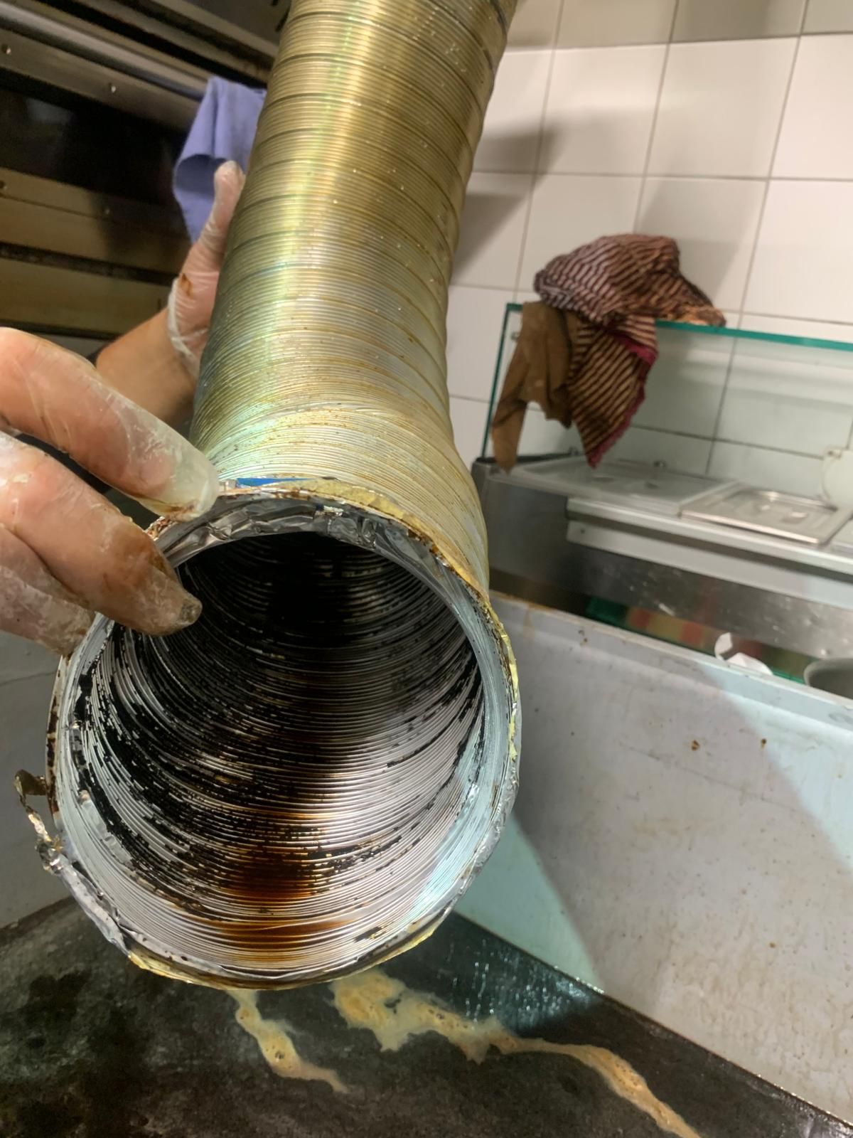 Une personne tient un tuyau sale dans une cuisine.
