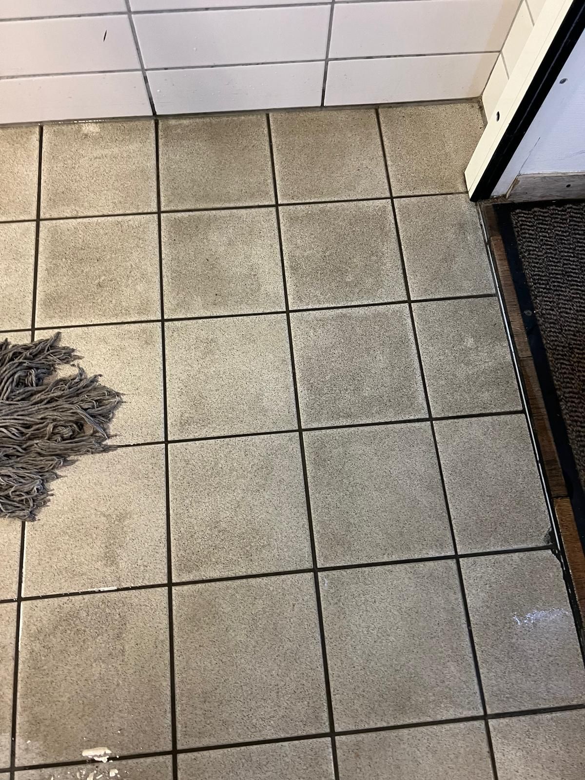 Une serpillère est posée sur un sol carrelé à côté d'une porte.