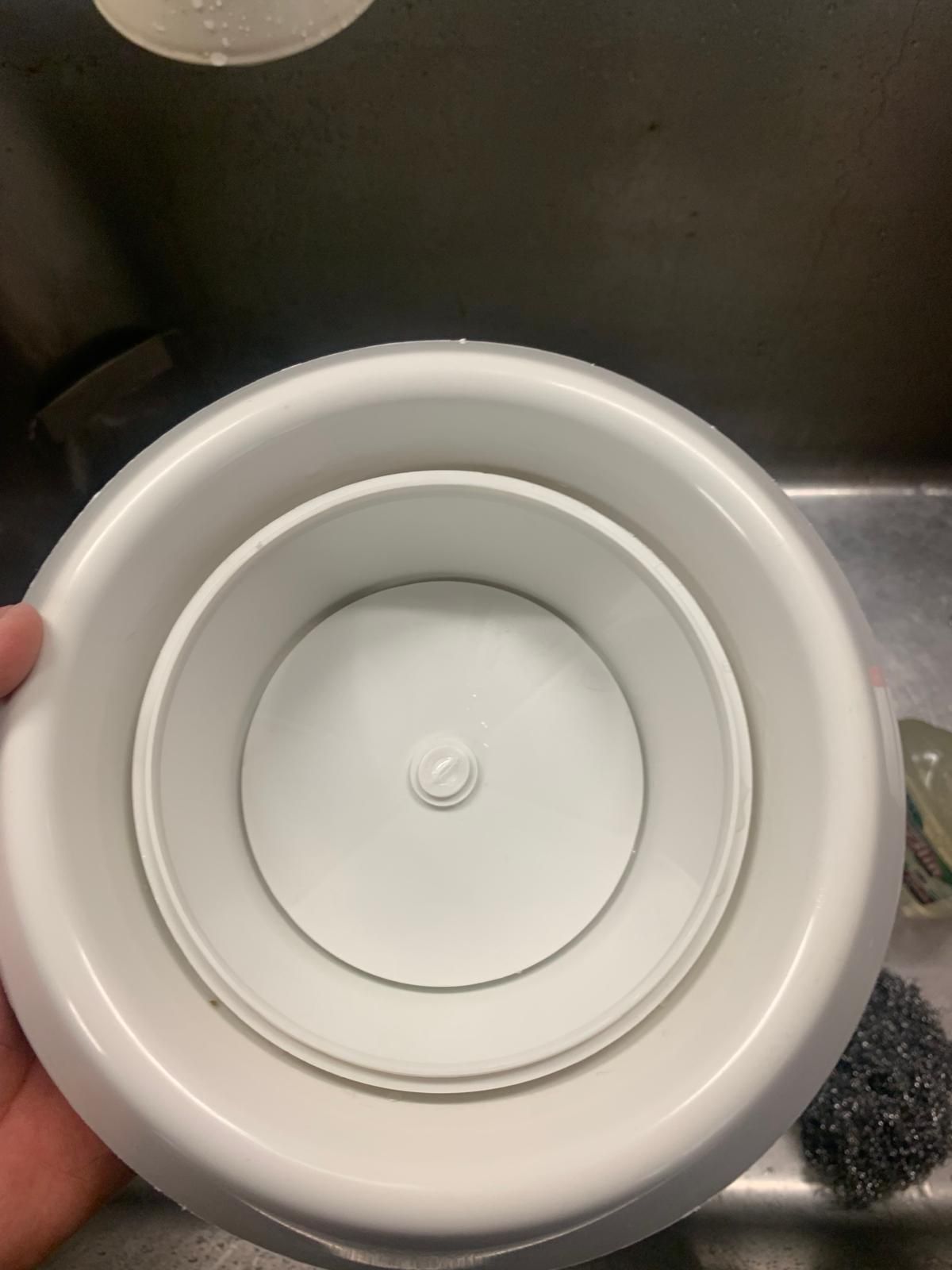 Une personne tient une assiette blanche devant un évier.
