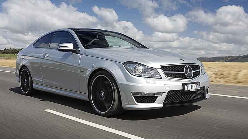 A silver car is driving down a road | Doctor of Motors