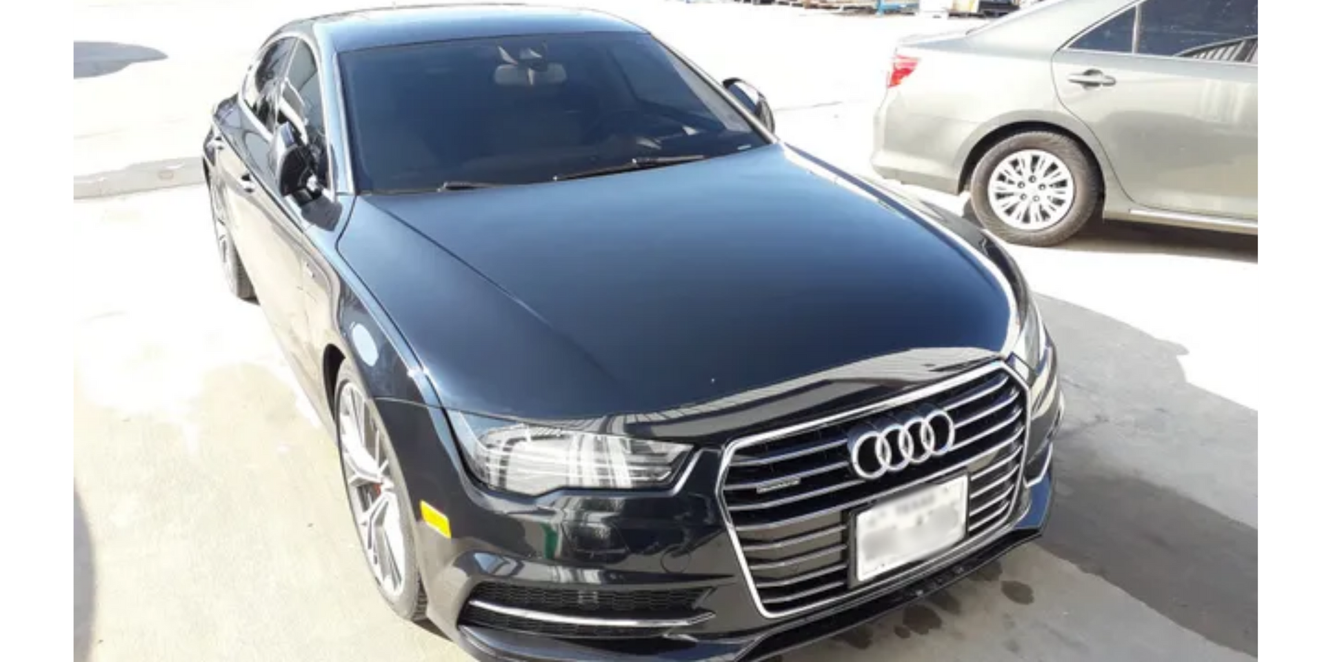 Black Audi sedan parked in bright daylight with a silver car beside it