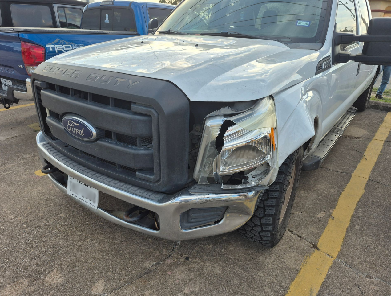 Damaged white Ford pickup truck with front-end collision, parked in a lot