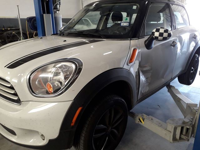 White Mini Cooper on a lift in an auto repair shop, front-left view