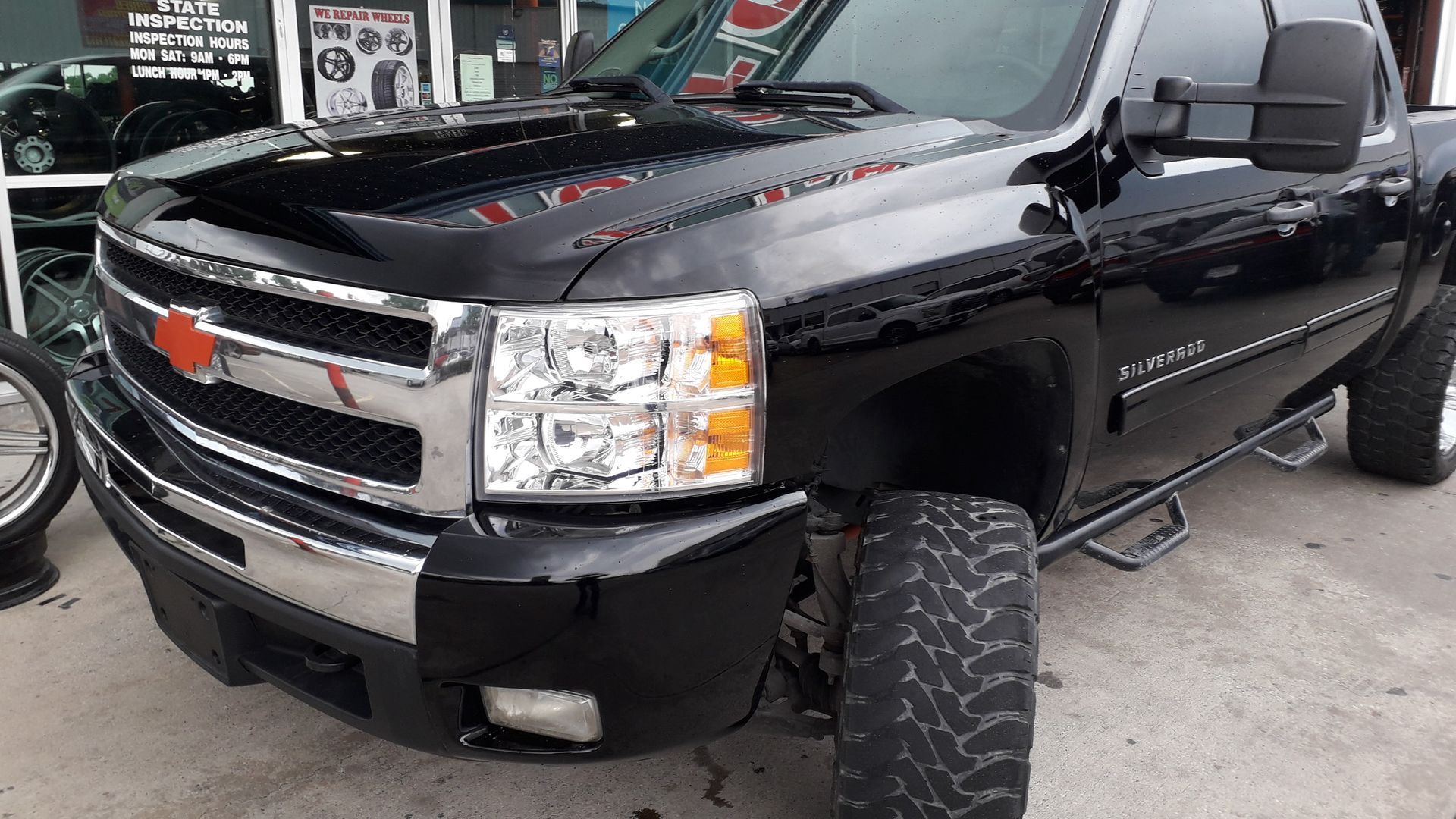 Black Chevrolet pickup truck with lifted suspension parked at an auto shop