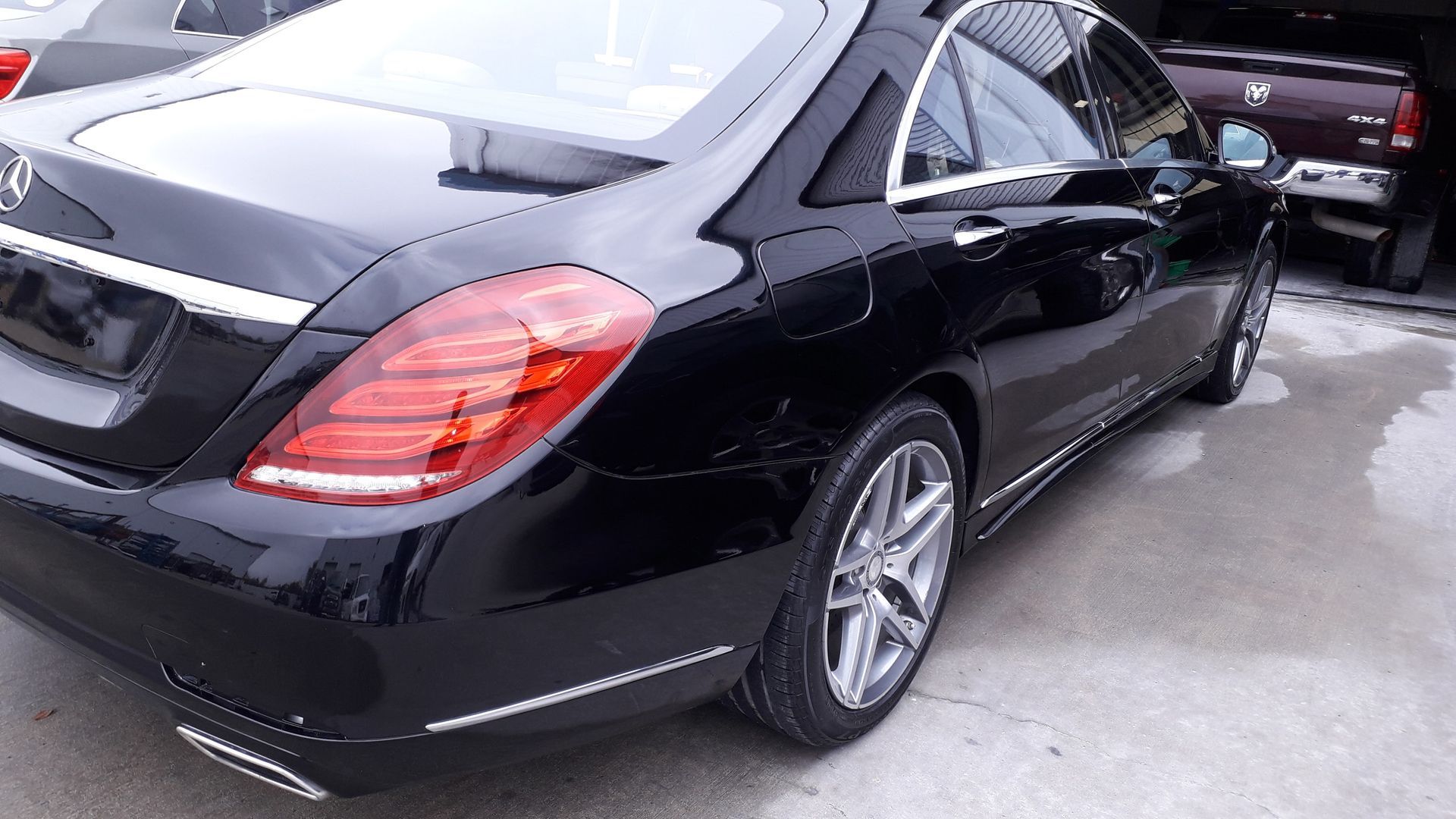 Black Mercedes sedan parked in a lot, rear side view with tail lights visible