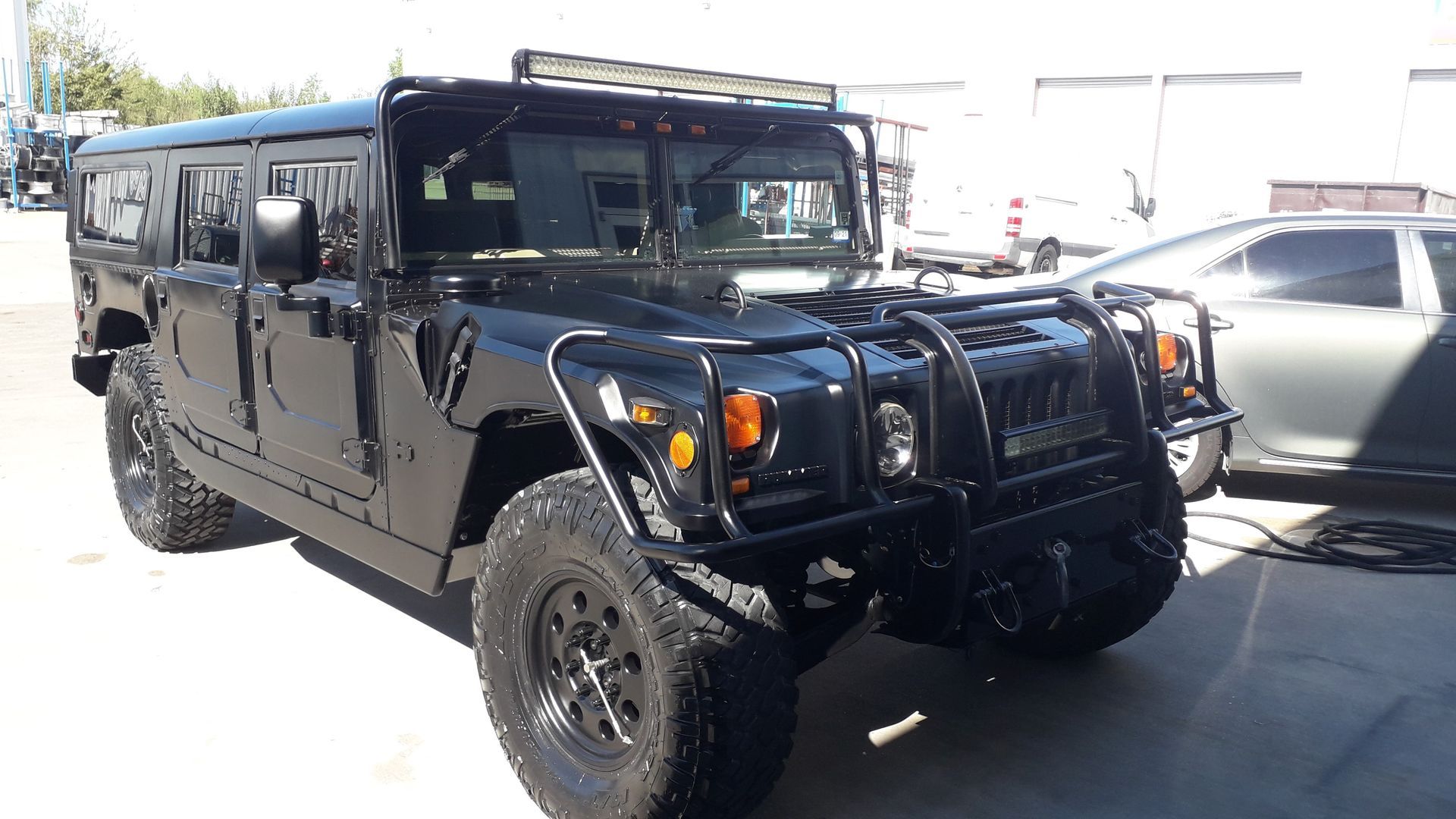 Black Hummer-style SUV parked outdoors, front view, with large off-road tires and tinted windows