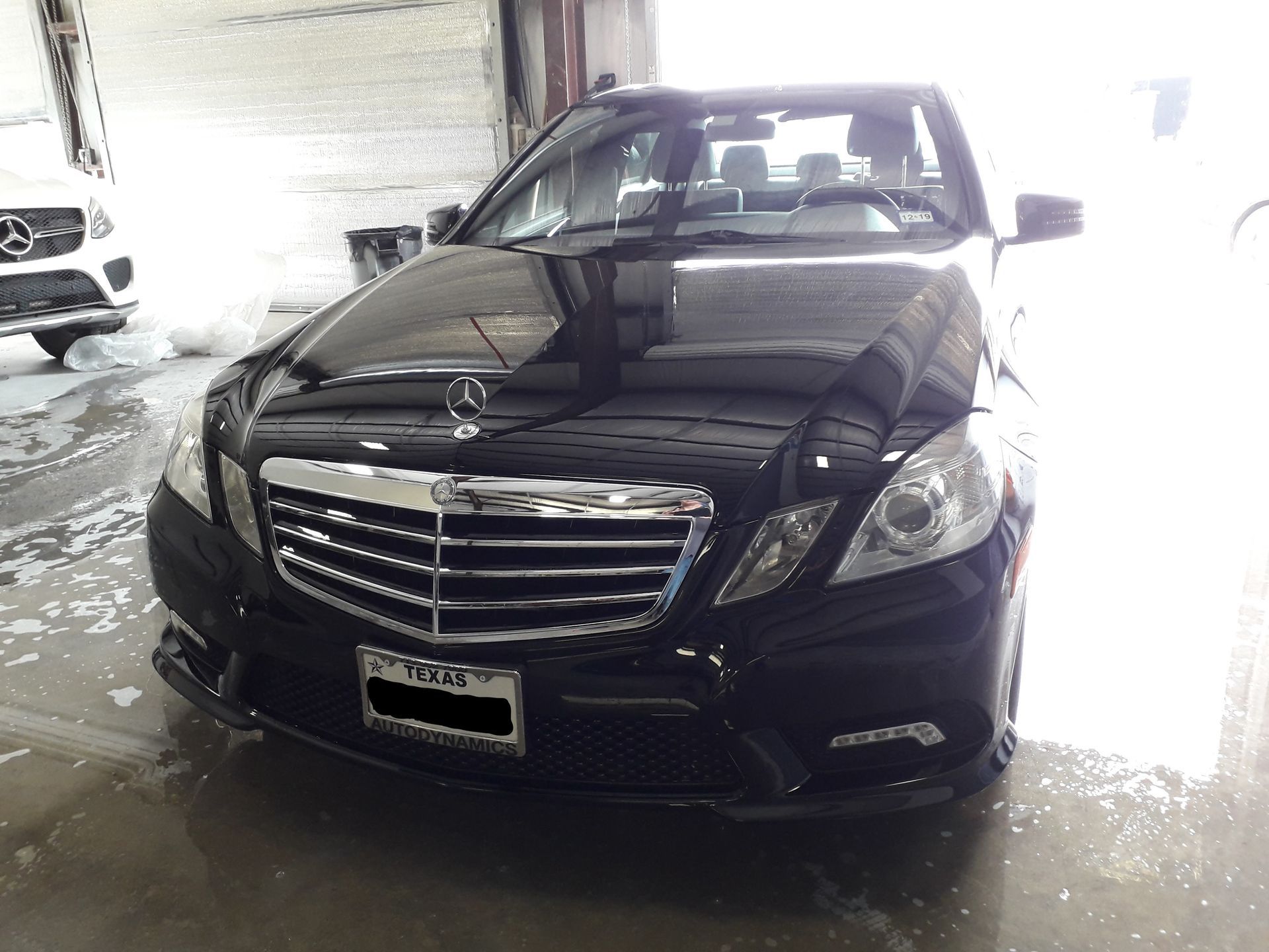 Black sedan parked indoors with a chrome grille, front view.