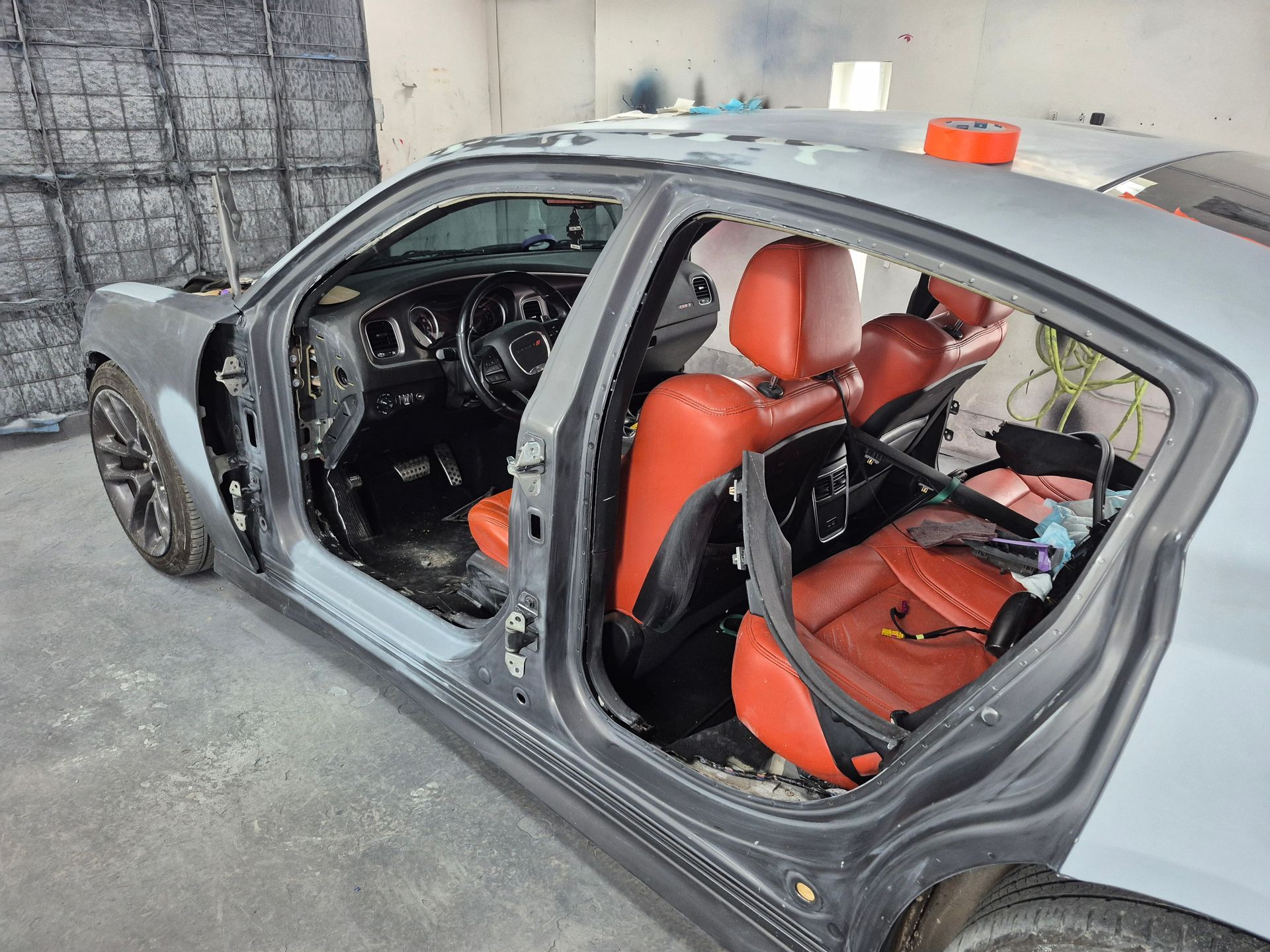 Partially disassembled gray car with red seats and exposed interior in a garage