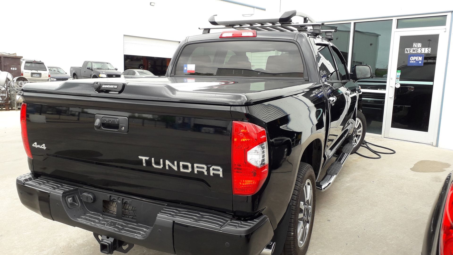Black Toyota Tundra pickup parked outside a dealership entrance