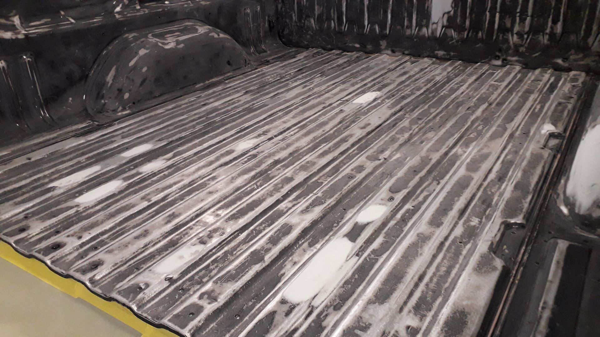 White ridged truck bed coated with slush, seen from the rear in a snowy setting