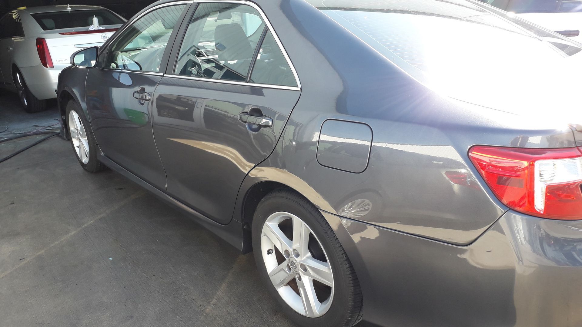 Gray sedan parked in a lot, side view with rear taillight visible