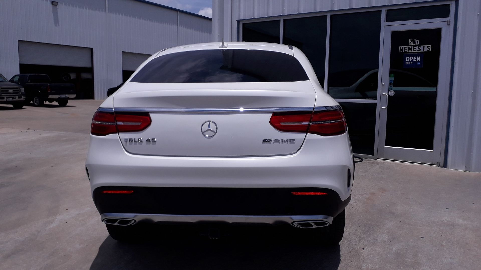 Rear view of a white Mercedes-Benz AMG SUV parked outside a building.
