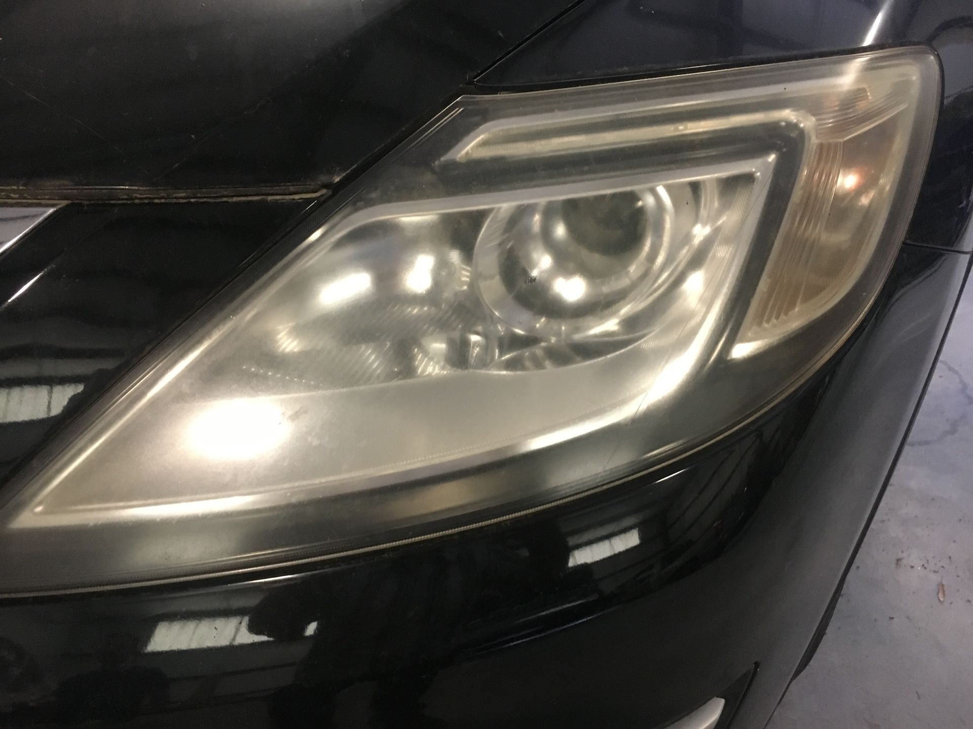 Close-up of a car’s front headlight assembly on a black vehicle