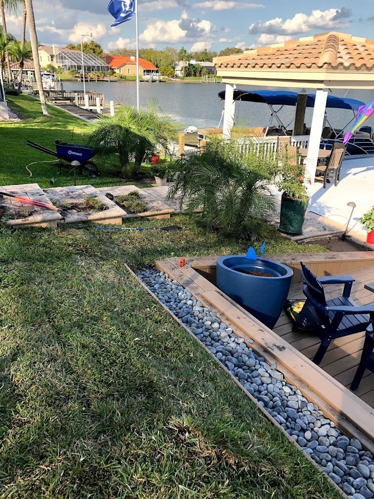 A lawn with a boat in the background and a blue pot in the foreground.