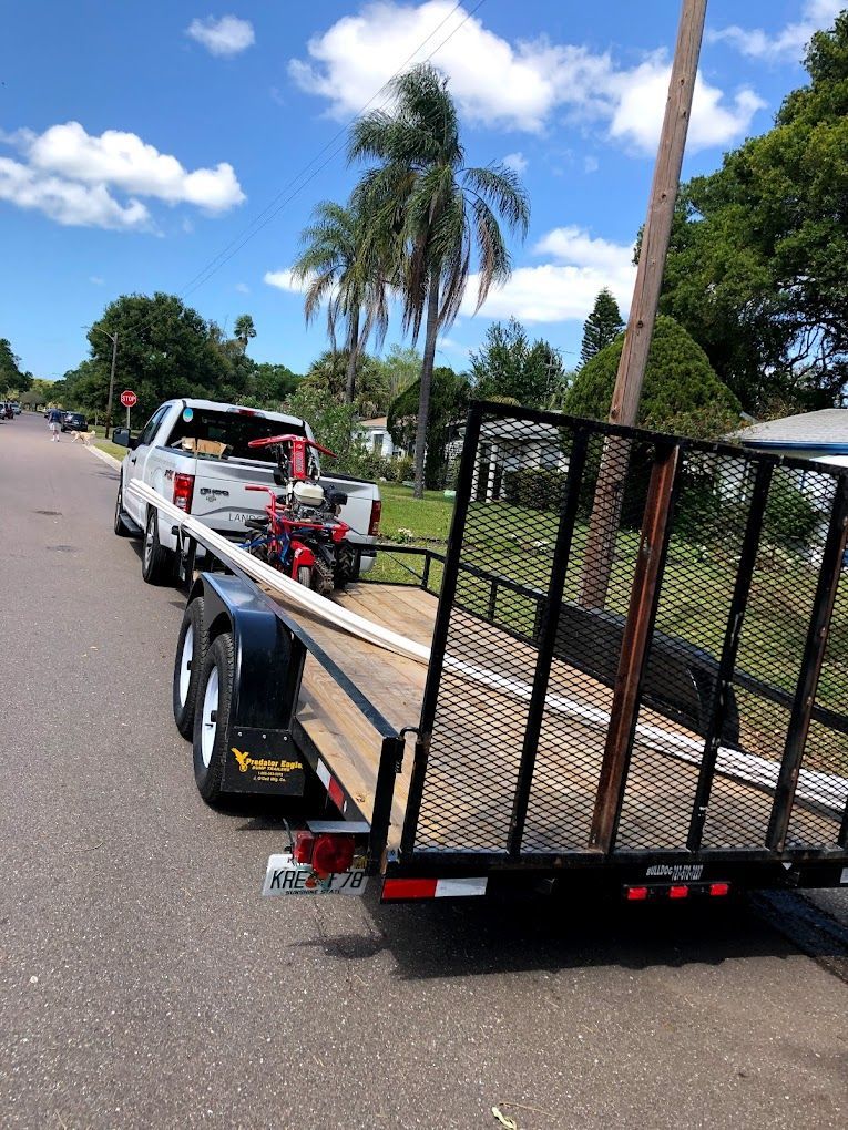 A truck is towing a trailer with a motorcycle on it.